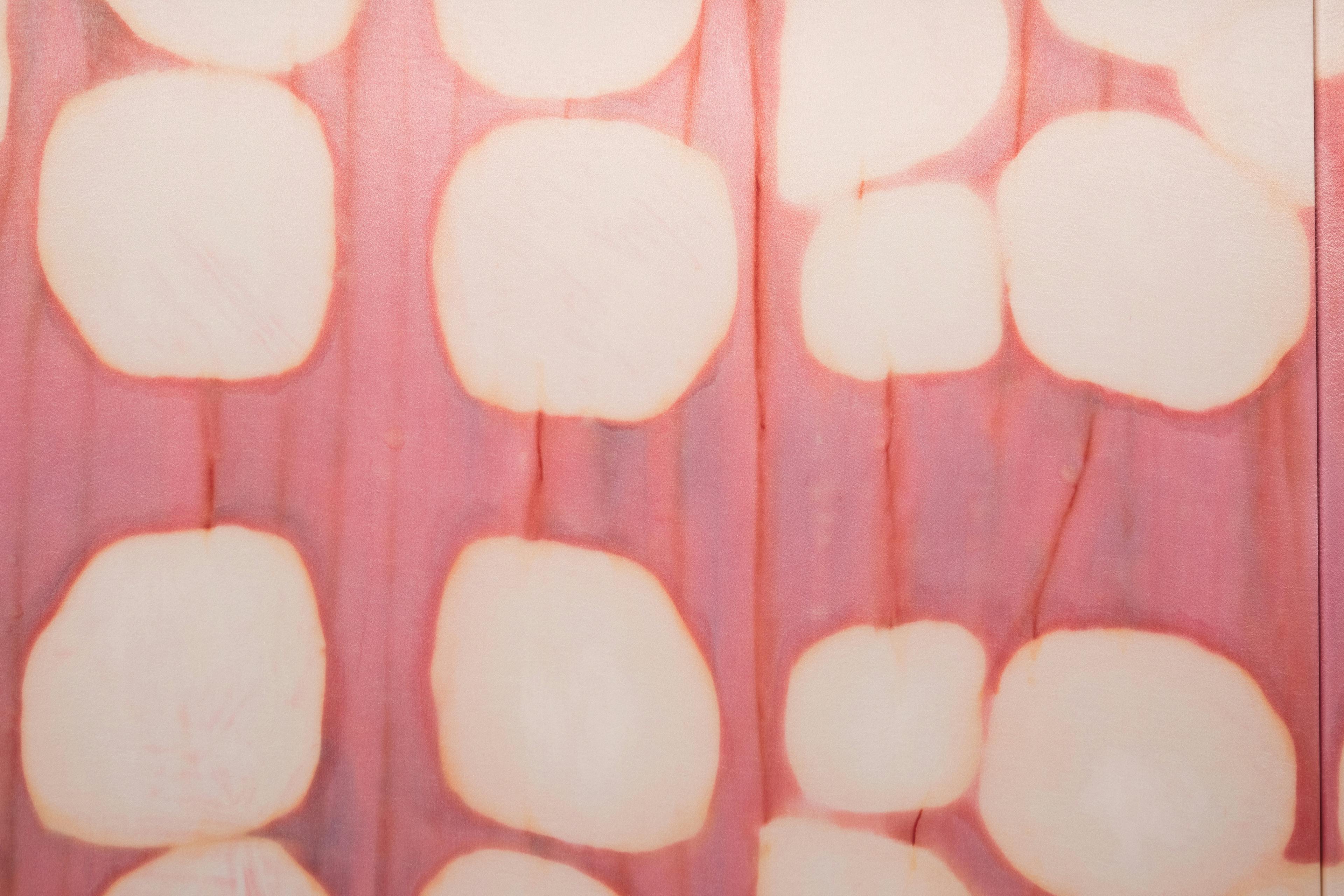 Detail of an abstract Max Boyla painting on silk with large white spots against a red and pink ground