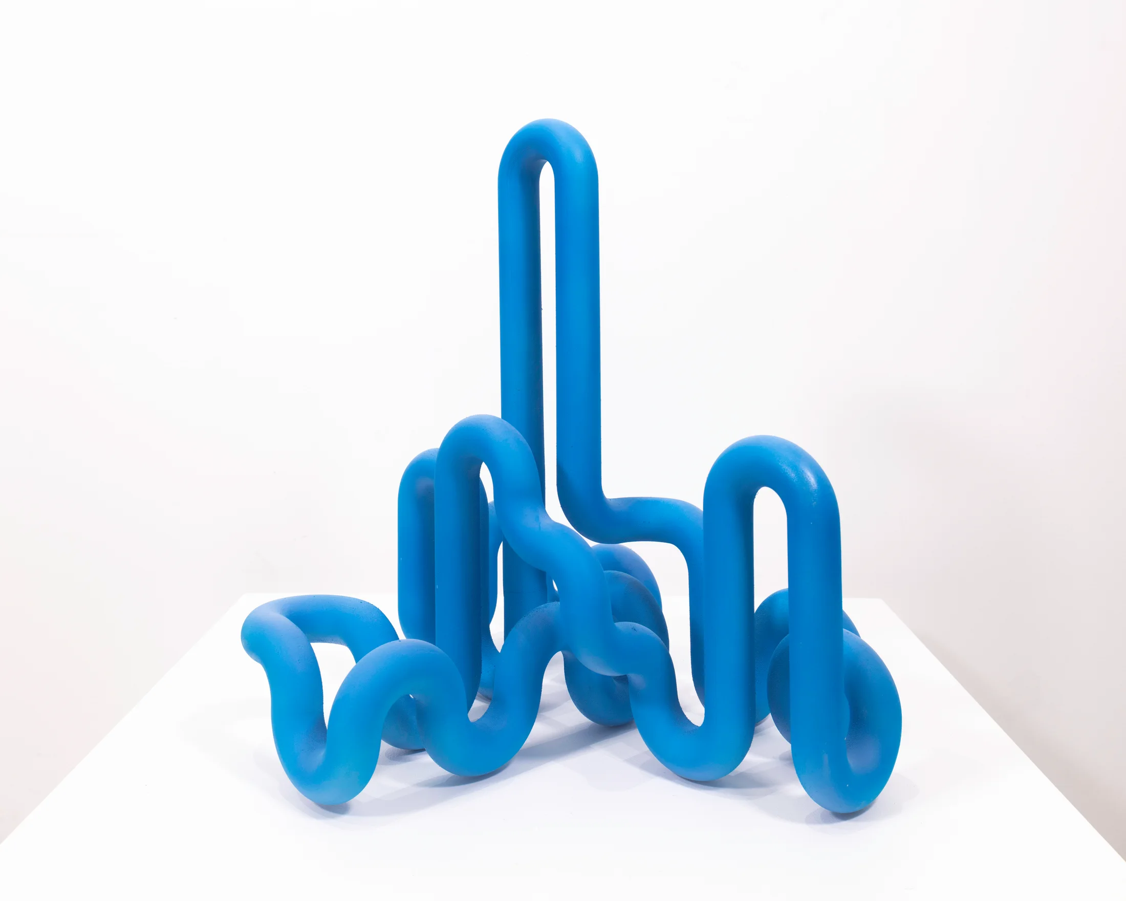 A bright blue sculptural artwork by Jacob Dahlgren made of PLA plastic that resembles a looping pipe