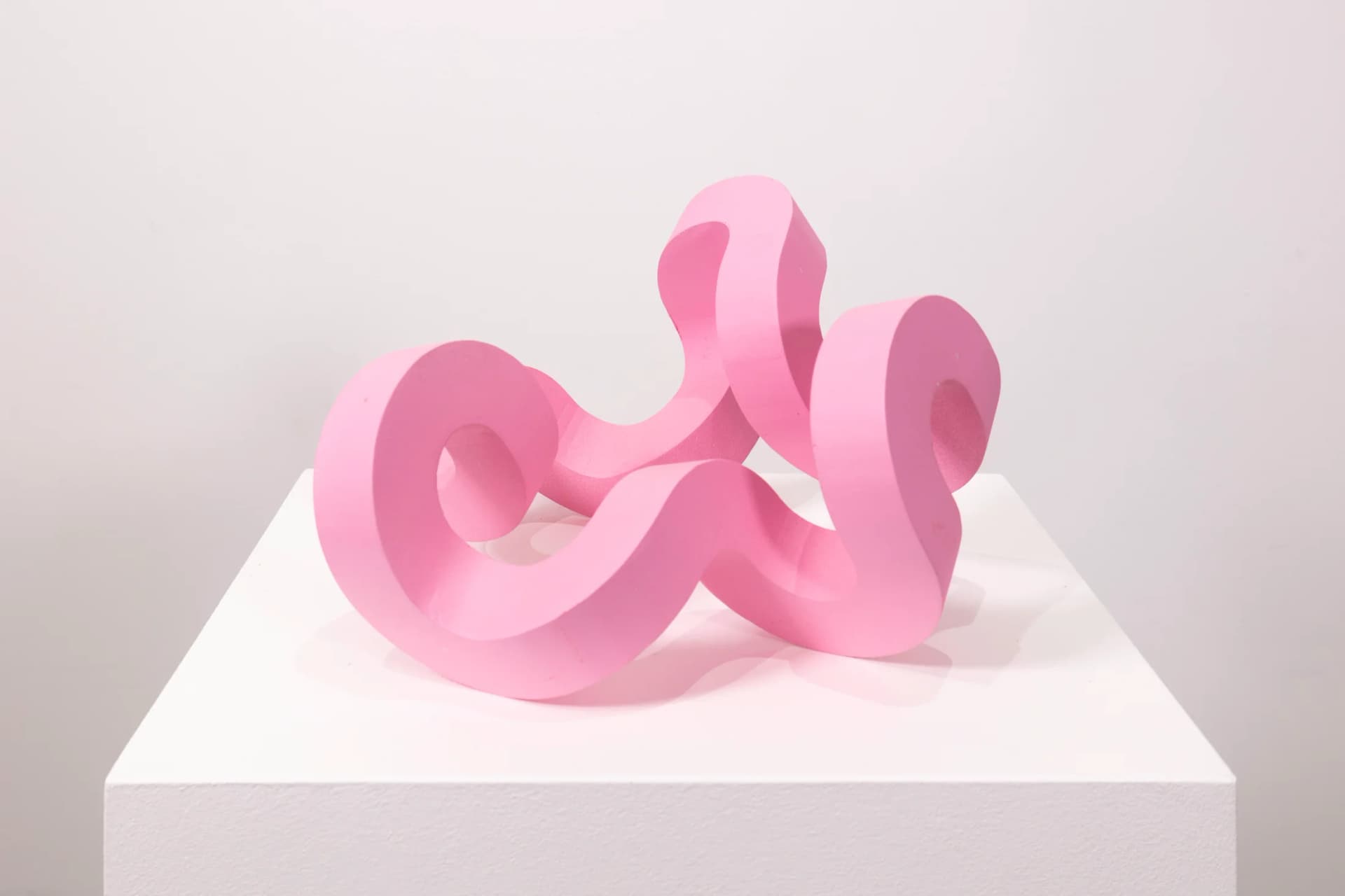 A bright pink sculpture by Jacob Dahlgren of a curved looping structure made from PLA plastic