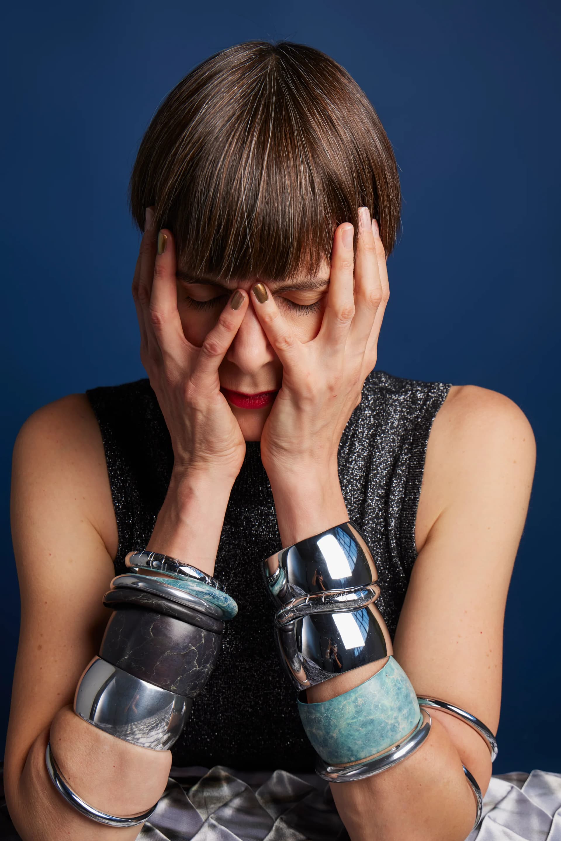 A portrait of Alice Channer covering her face with her hands